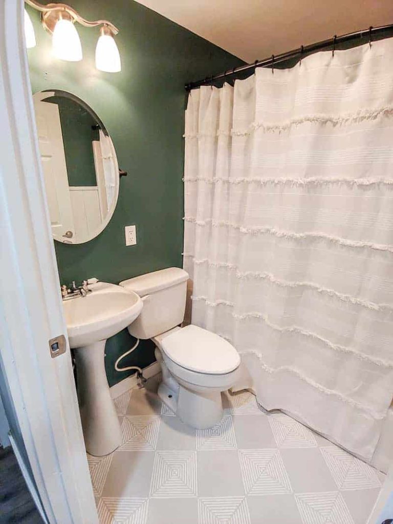 Our boho chic guest bathroom looks great with newly painted tile floors, painted with a white and gray geometric pattern and bold teal walls