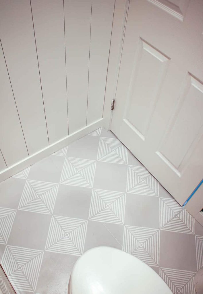 Our gorgeous painted tile floor in our guest bathroom, painted with white and gray tile paint with geometric stencils