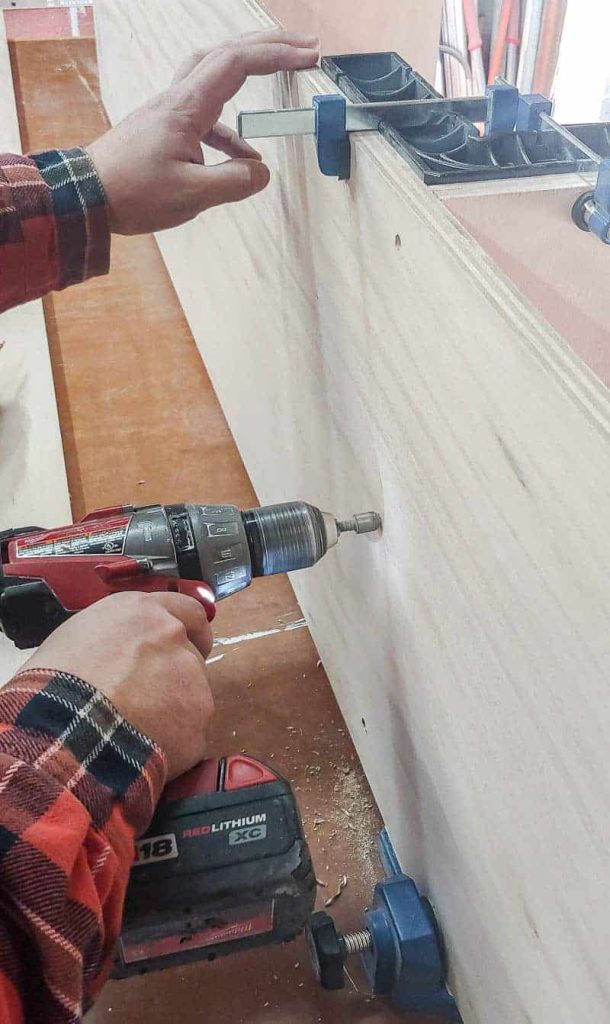 shows a man screwing cabinets to assemble into the side of the plywood 