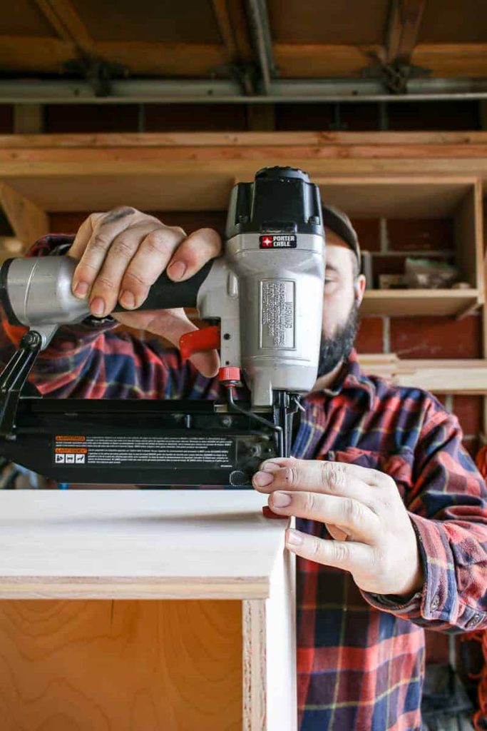 shows a man nailing holes into the top of the plywood to help connect two pieces