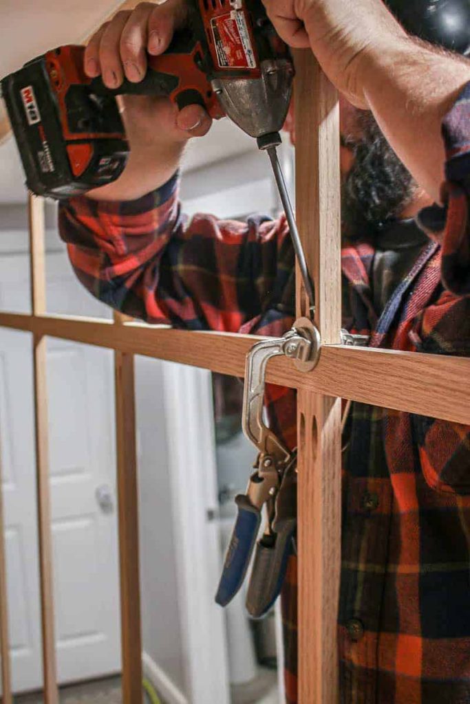 shows a man drilling a screw into pocket hole on the back of a wood face frame 