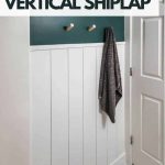 shows an angled view form the tub of the white vertical shiplap all with top half being dark teal and white door with gray floors with white stripes with overlay text that says cheap and easy vertical shiplap