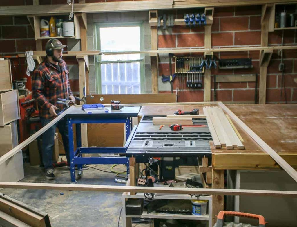 shows a garage and a man putting together a wood face frame on a table