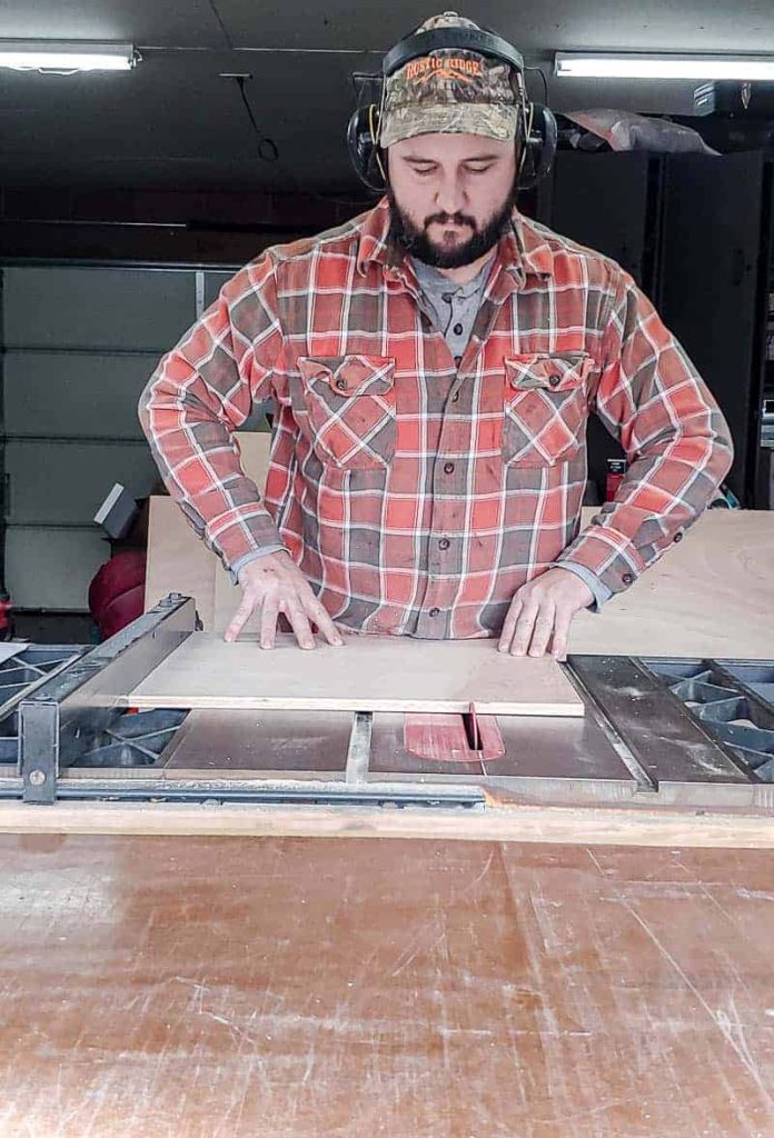 shows a man with ear protection using a table saw to cut plywood