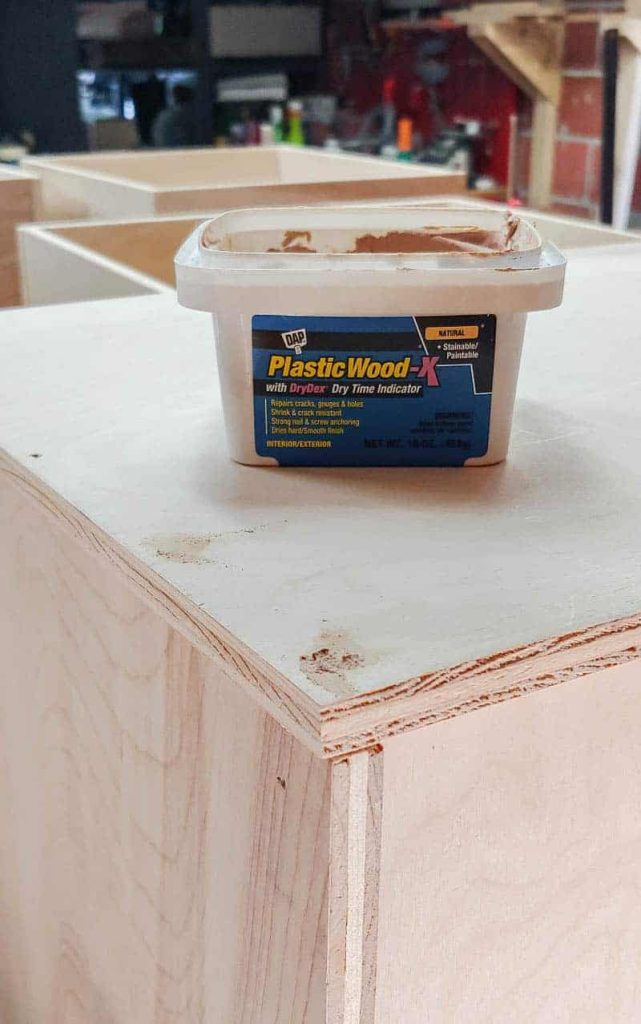 shows a box of DAP plastic wood-X sitting on top of the plywood