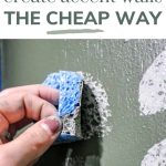 shows an up close picture of a hand stamping a gray painted half circle sponge to a green wall painted with other half circles with text at top that says learn how to create accent walls the cheap way