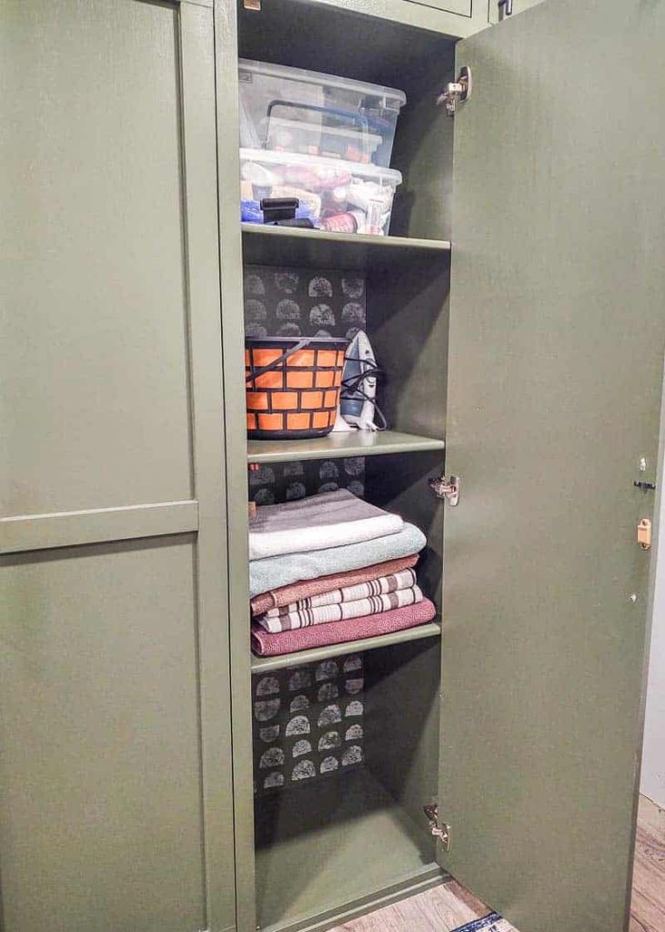 shows the inside of the green DIY mudroom lockers that have folded towels and buckets on the shelves with white painted sponge painted pattern