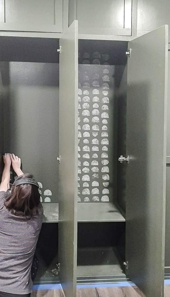 woman painting with sponge semi circle on the back of mudroom lockers