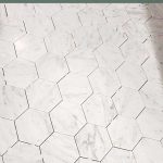 White marble hexagon tile floors with spacers and no grout with text overlay that says bathroom tile floor tutorial for beginners!
