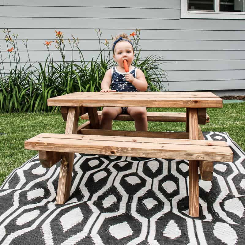 This little toddler is enjoying a refreshing summer popsicle at an adorable toddler sized picnic table for kids