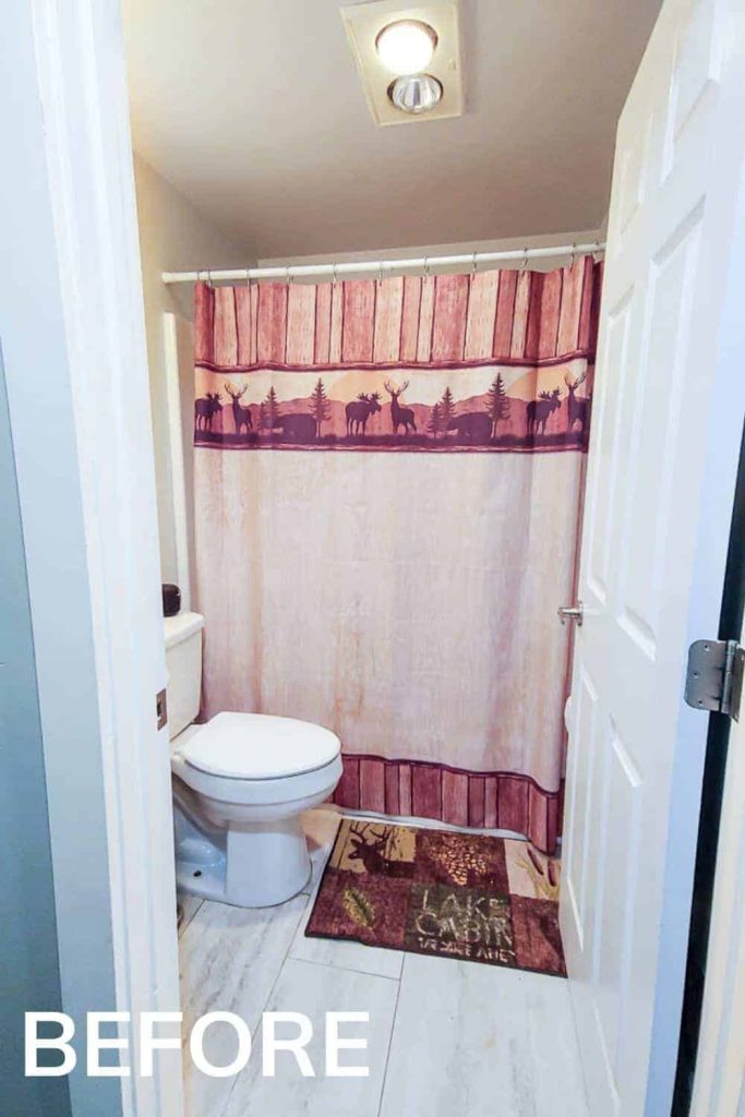 the inside of our small guest bathroom is a boring white color with outdated tile and a cabin themed shower curtain and bath rug