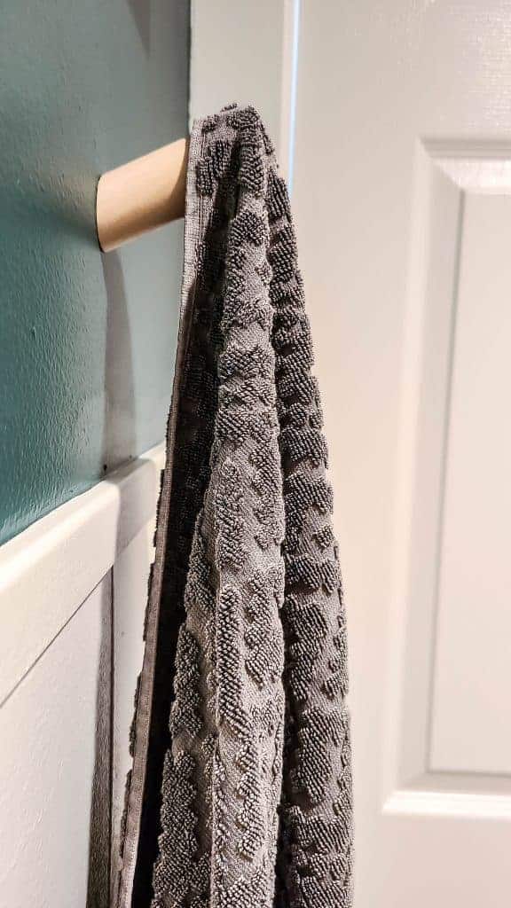 An up close look at the new towel holders - simple wooden pegs mounted to the wall, holding a textured grey bath towel