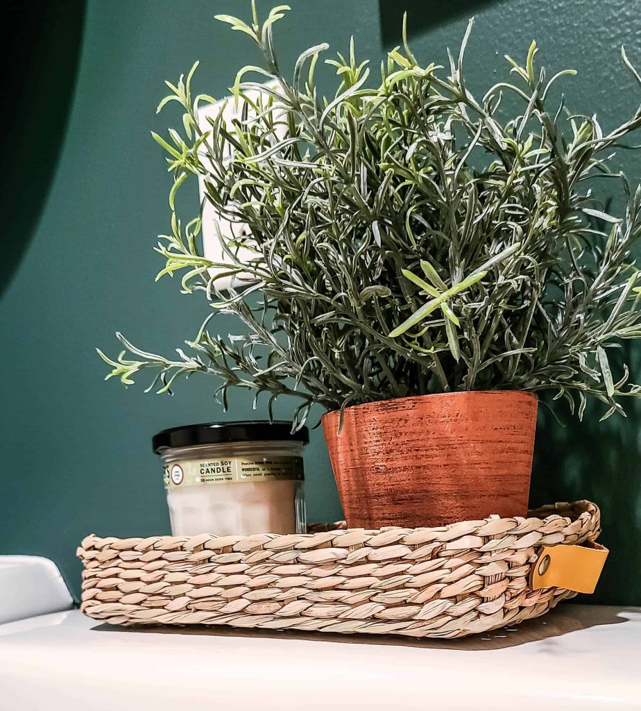 We decorated our guest bathroom with a faux indoor plant and candle, which sit in a wicker basket on the back of the toilet.