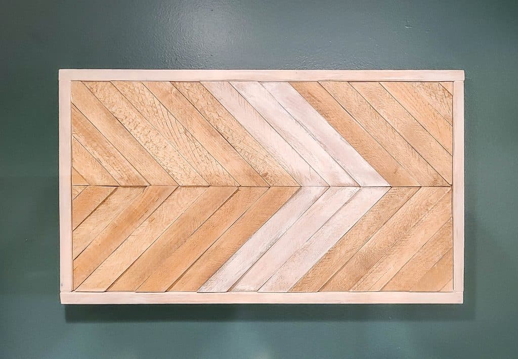 shows the piece of boho wood wall art on a dark green wall