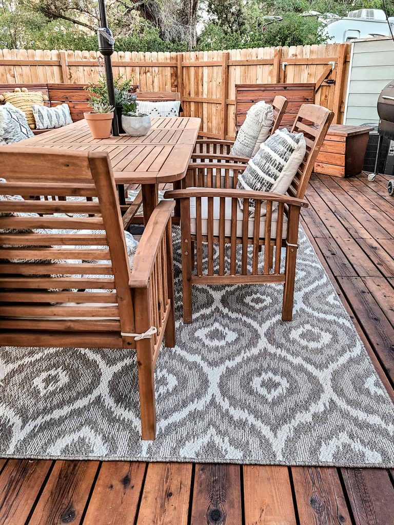 Our new outdoor dining table and chairs match the dark wood of our deck. The patio chairs have comfortable cushions and throw pillows that match our new outdoor area rug.