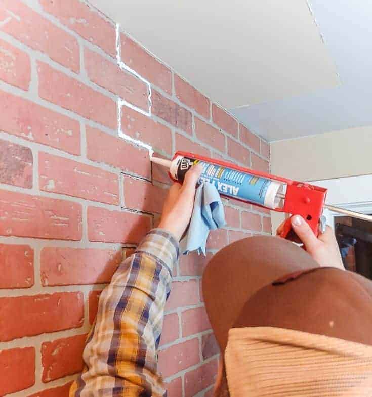 Using caulk to fill in bricks on a wall.
