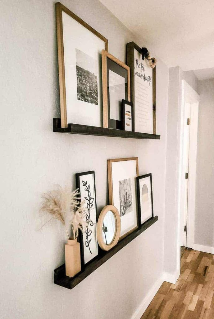 Styled DIY picture ledge shelves filled with frames and decor in a hallway
