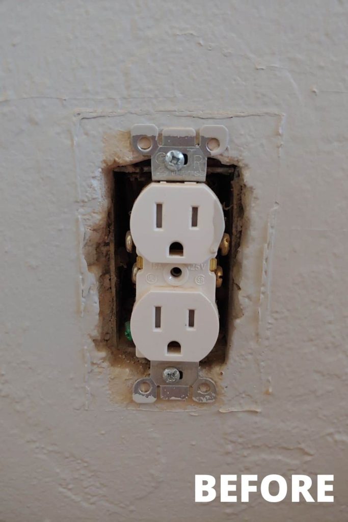 A close up image of a white electrical outlet on a wall without a cover.