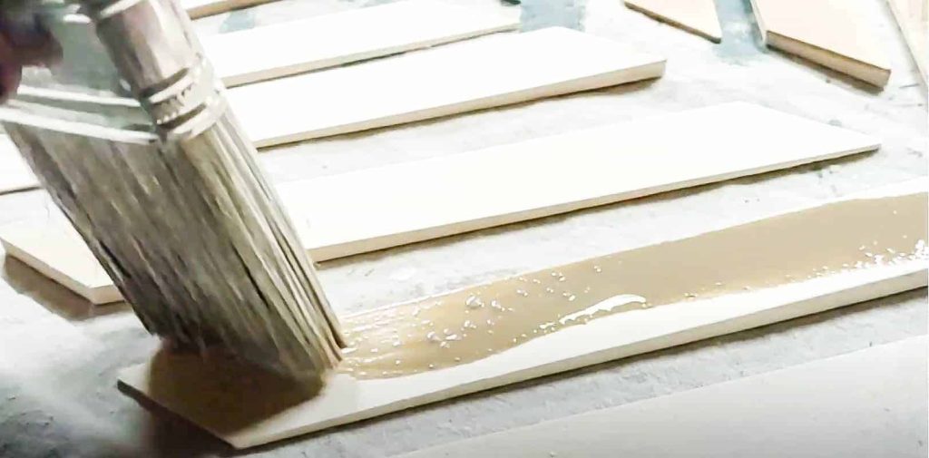 shows a paint brush staining the small diagonal cut piece of wood