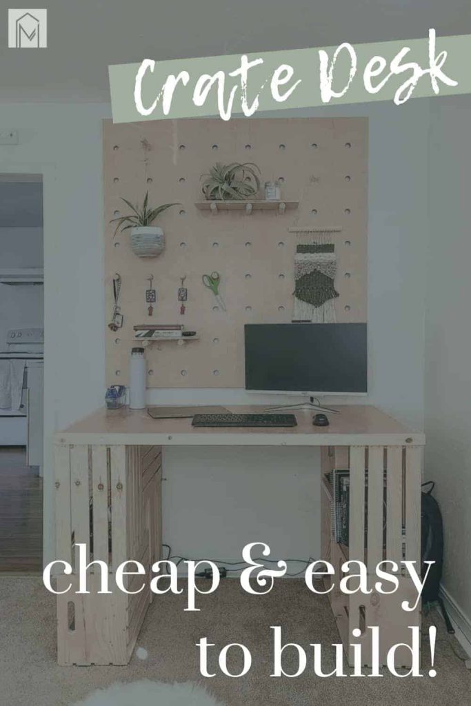 shows a face on view of the wood crate desk with a computer on it and a wood wall behind it with overlay text that says crate desk, cheap and easy to build