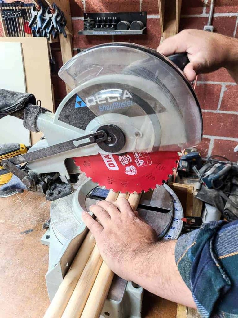 Using a miter saw to cut down the dowel rods that we'll be using in our giant pegboard wall.