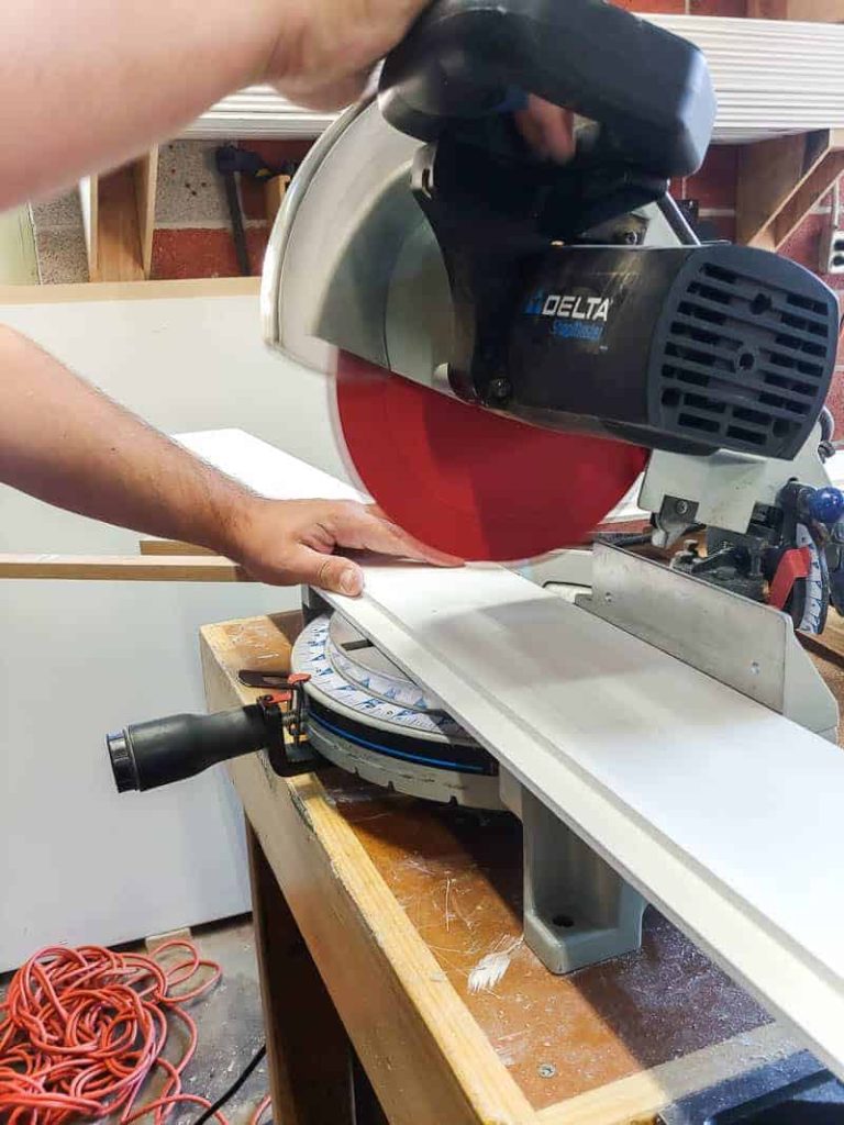 My husband pictured here, using a miter saw to cut shiplap planks before attaching them to the ceiling