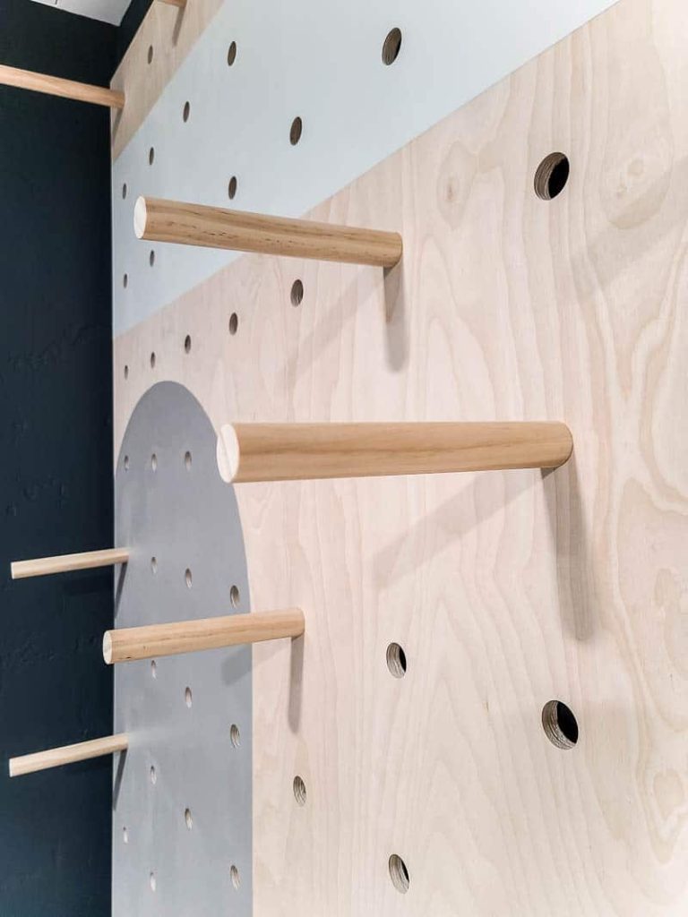 Installing the dowel rods in various positions to create shelves on the giant pegboard wall.