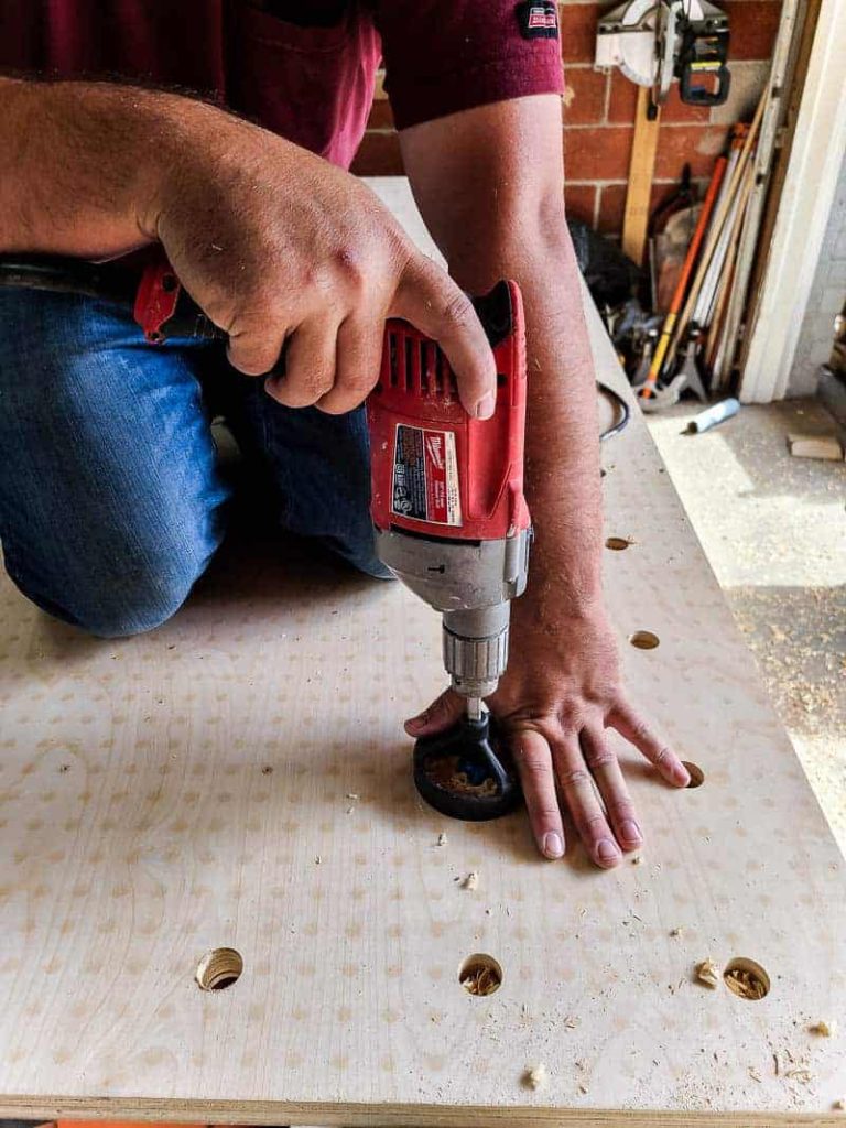 Using a drill guide for larger bore holes to insert dowel rods into our pegboard wall.
