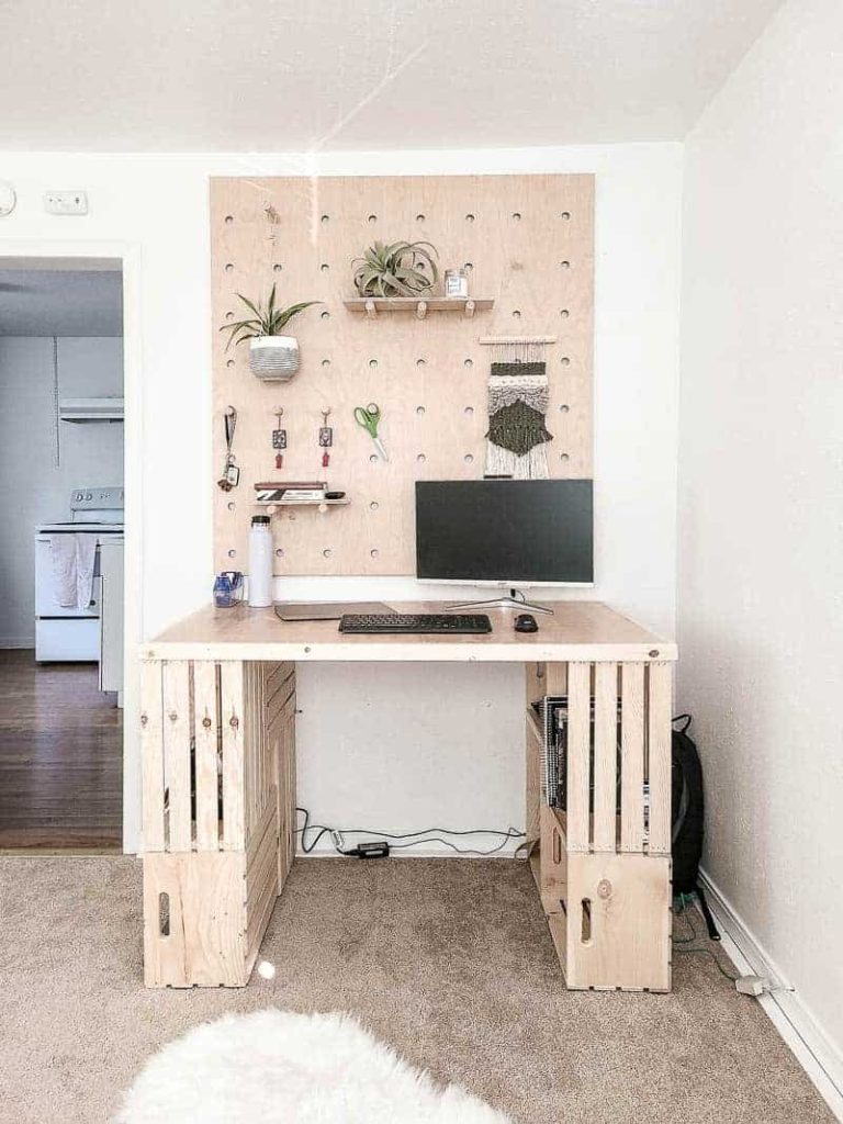 wood crate desk with a computer on it and a wood storage wall behind it 