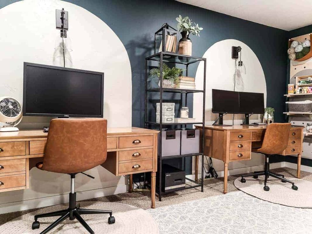 shows his and hers wood desks in a dark teal room with white painted arches and white rugs