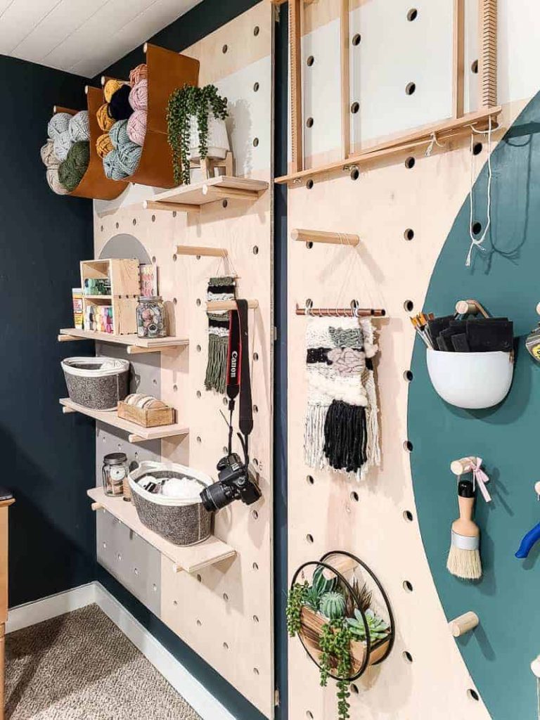 Our giant pegboard wall is completed, painted with fun shapes and patterns, and styled with shelves and pegs to hold crafting supplies and other storage
