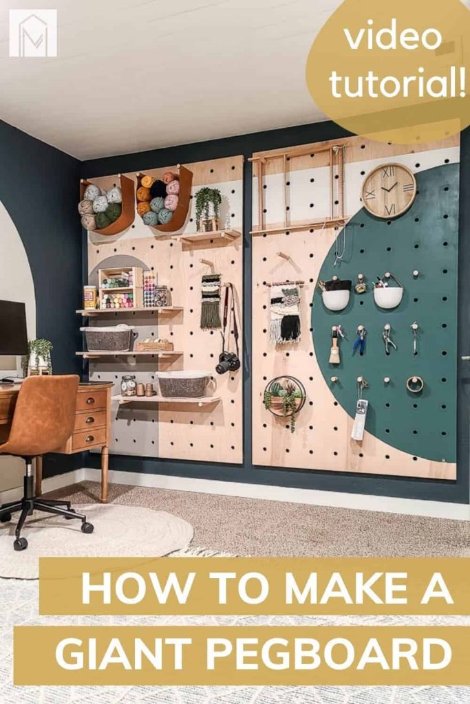 Our completed, painted giant pegboard wall hangs, styled with craft supplies and decor organized on dowel rod pegs and shelves. Text overlay reads 