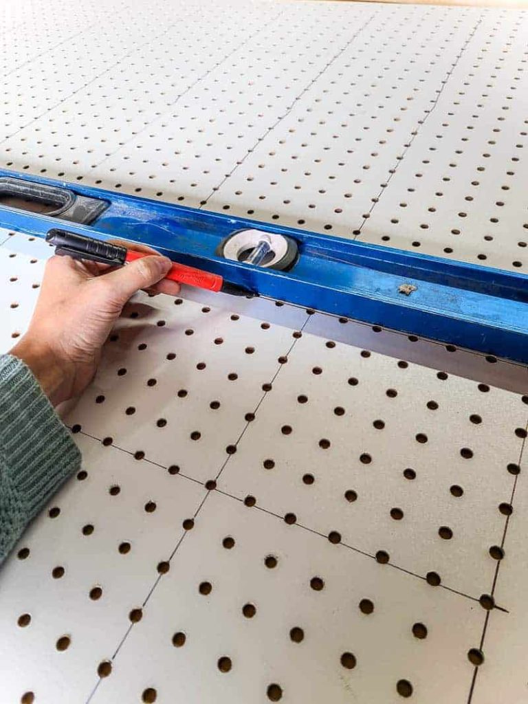 Using a level and Sharpie marker to draw lines along MDG pegboard.