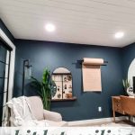 Home office decor with arm chair and dark greenish blue walls with white planked ceiling with text overlay that says shiplap ceiling cover popcorn texture