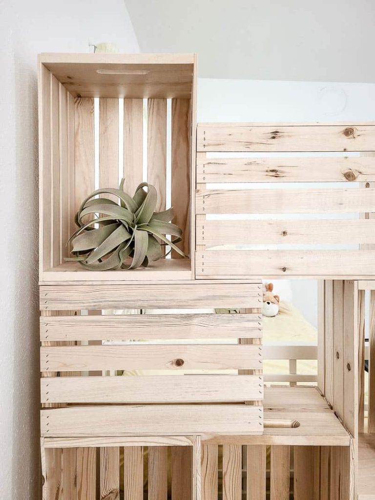 shows an up close picture of the wood crate bookshelf wall with a plant in one of the crates