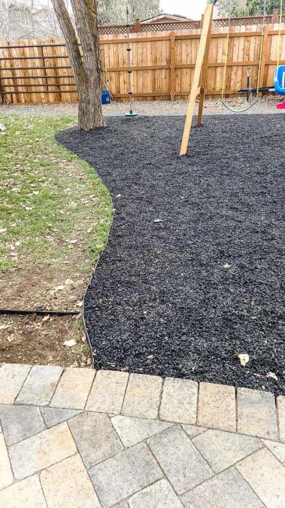 Image of Pile of black rubber mulch in a backyard