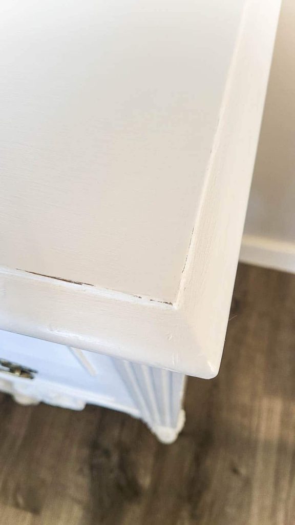 The corner of the vintage wood desk, repaired and repainted with white chalk paint.