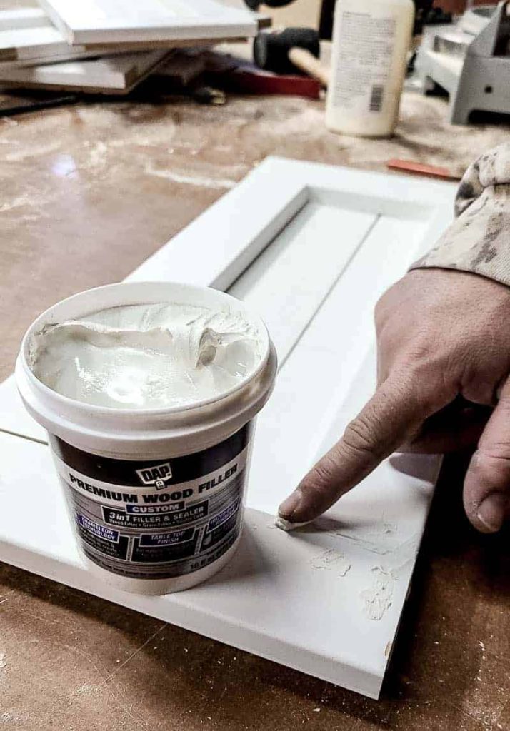 shows wood filler being applied with finger to nail holes