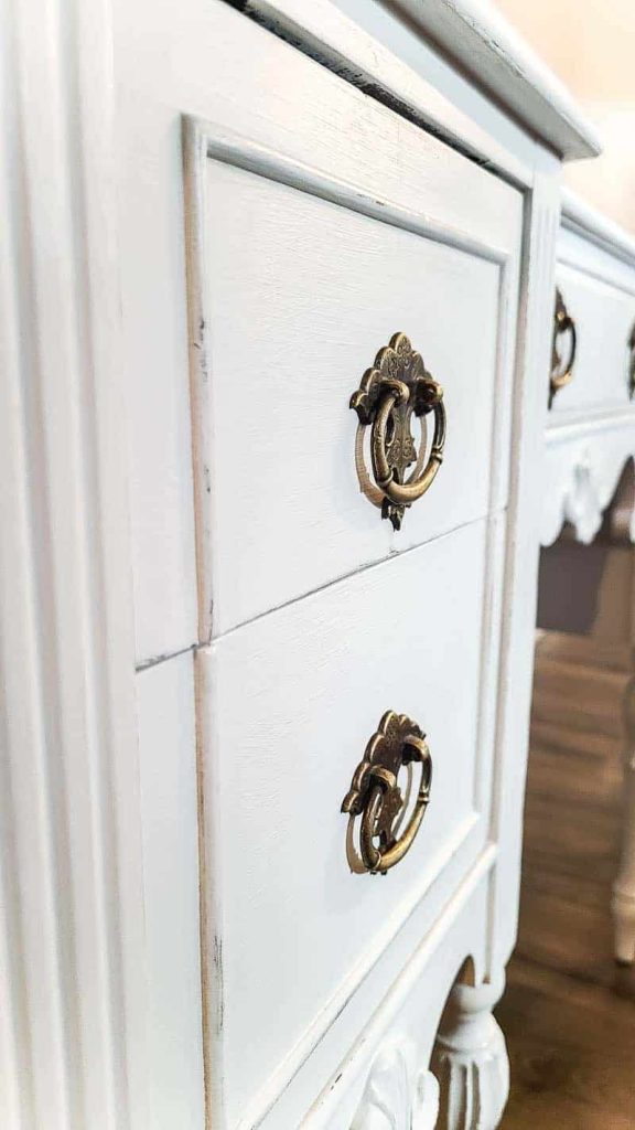 A close up look at the drawers on the vintage wood desk, repaired and repainted with chalk paint. The drawers have ornate brass handles.