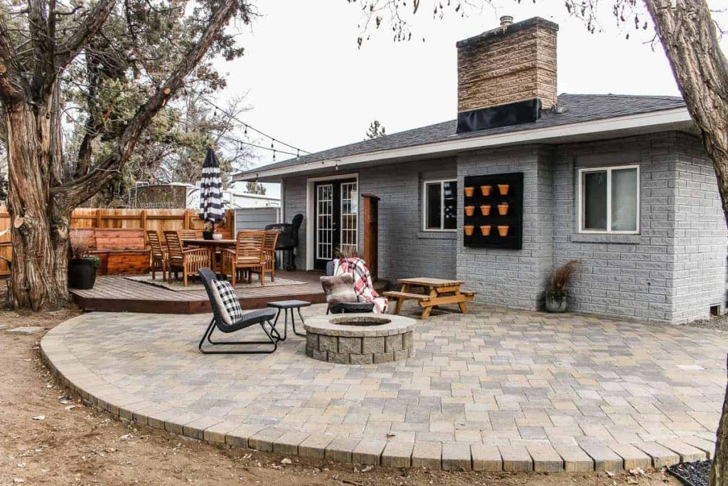 A patio with fire pit is finished, chairs are placed next to the pit