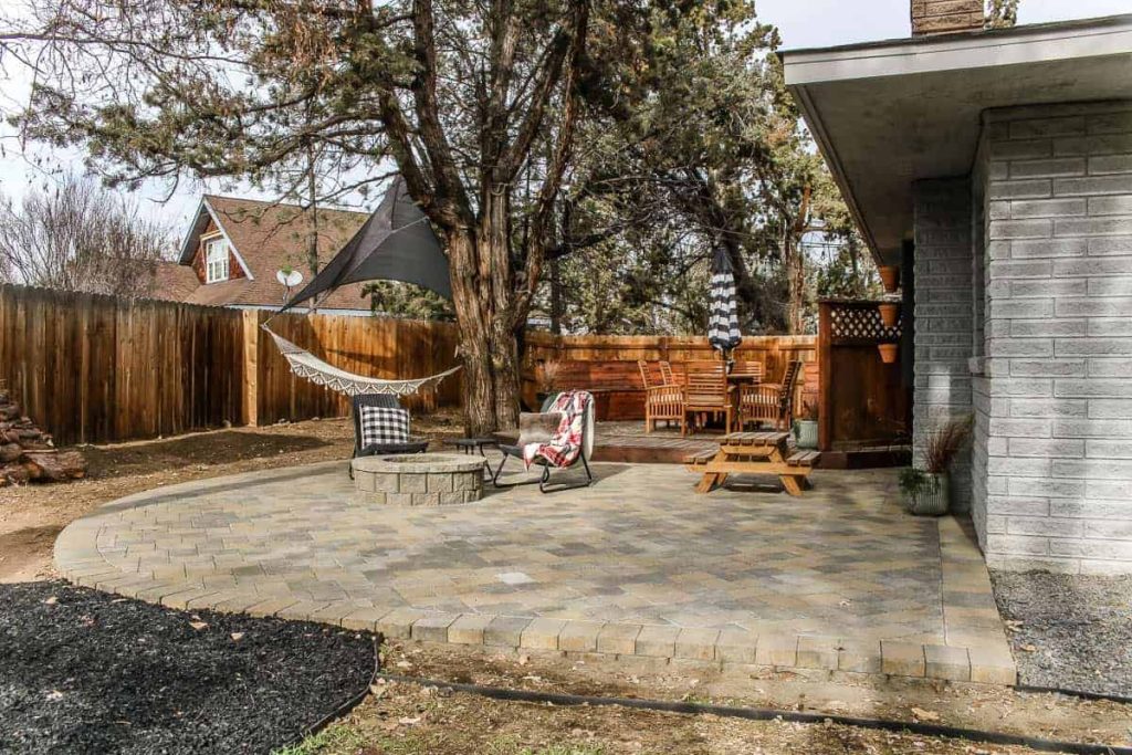 patio space is shown from a distance with wood deck and outdoor dining furniture in background