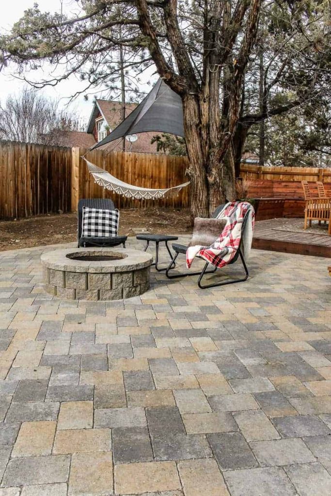 chairs sit next to fire pit, a hammock is in the background