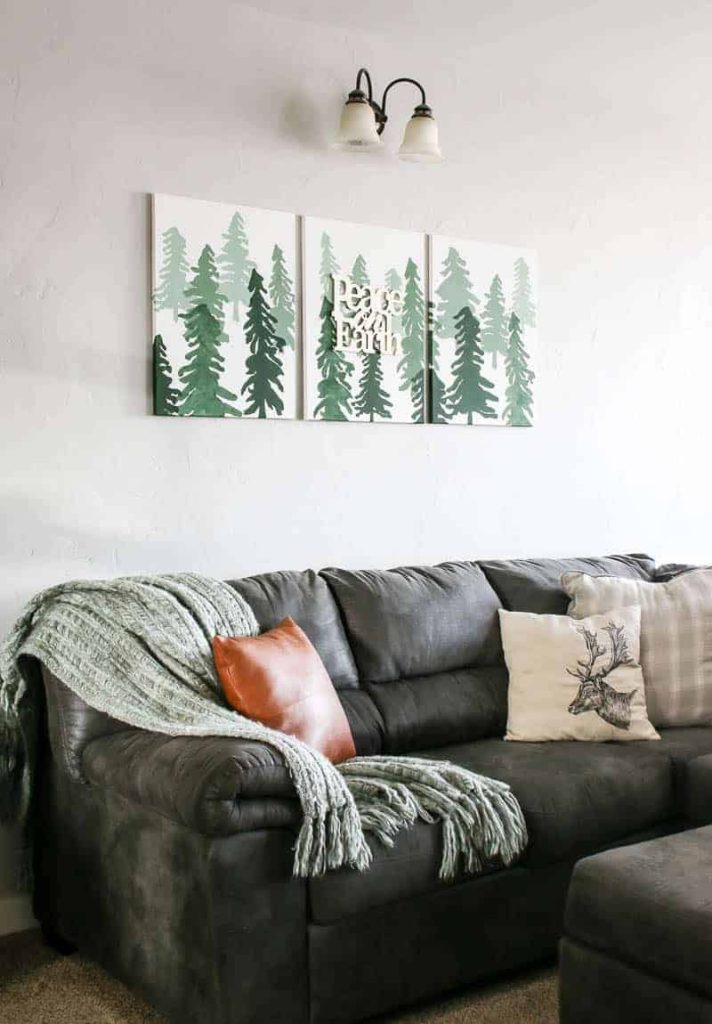3 Christmas tree canvases hanging over a gray couch