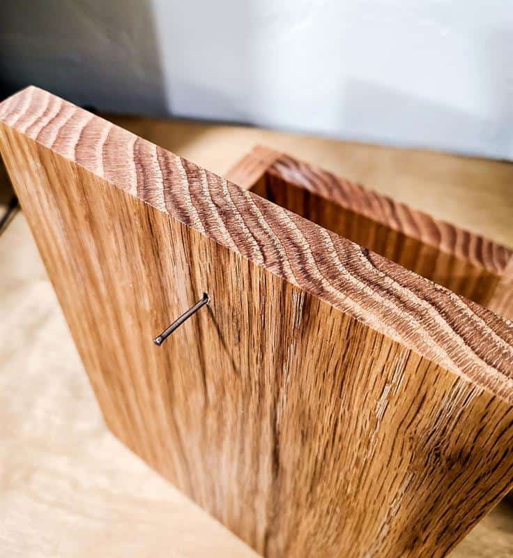 Nails are being attached to serve as clips for securing items to the wood, such as for the desk calendar and wooden pencil holder.