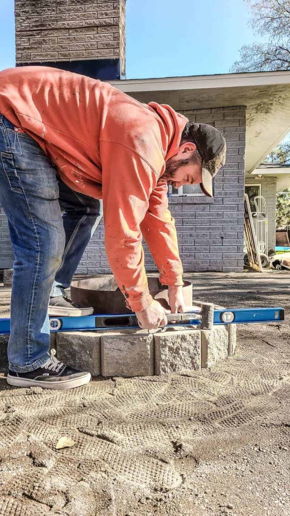 shows a man leveling out the pavers