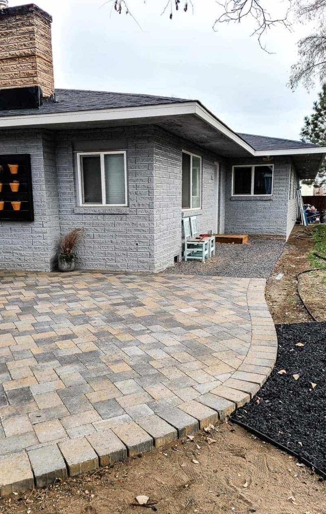 shows paver patio with curved edges and gravel by backdoor
