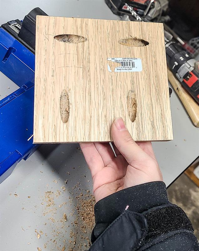 An individual is holding a piece of wood, preparing to drill into it.