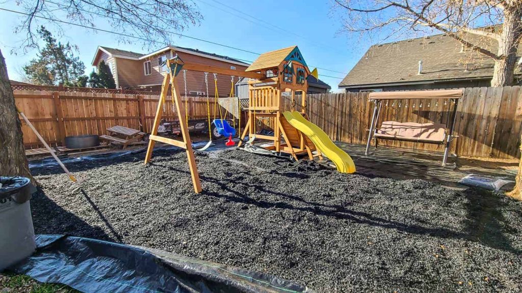 installing black rubber mulch on play area in back yard