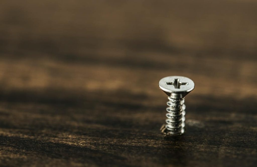shows a screw getting pushed into dark wood