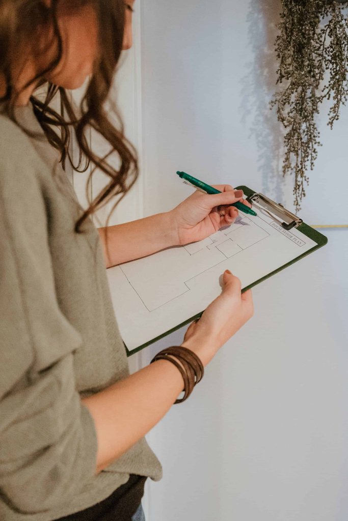 Woman writing a floor plan on a piece of paper on a clipboard 